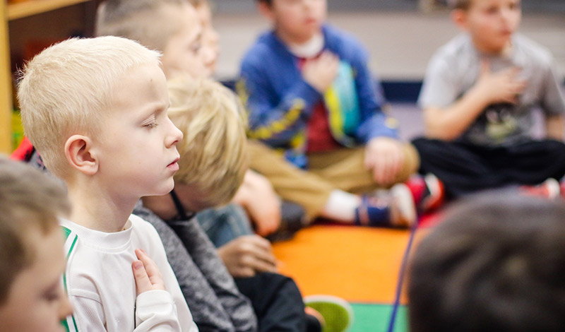 Crianças meditando em sala de aula